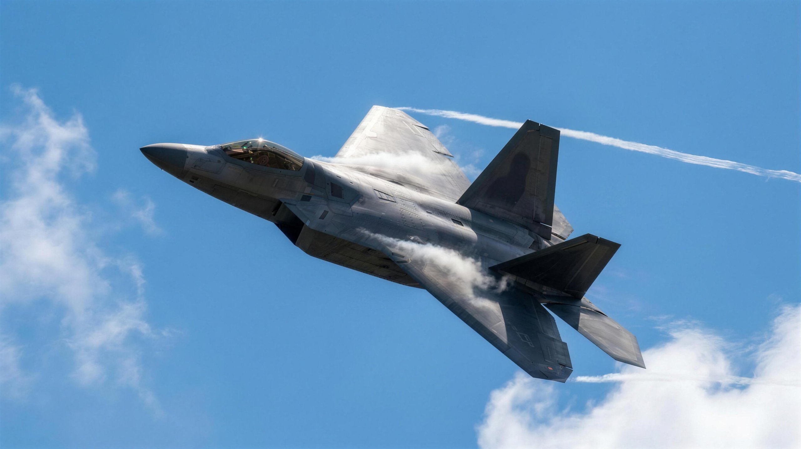 Stealth fighter in a high-G bank against a bright blue sky